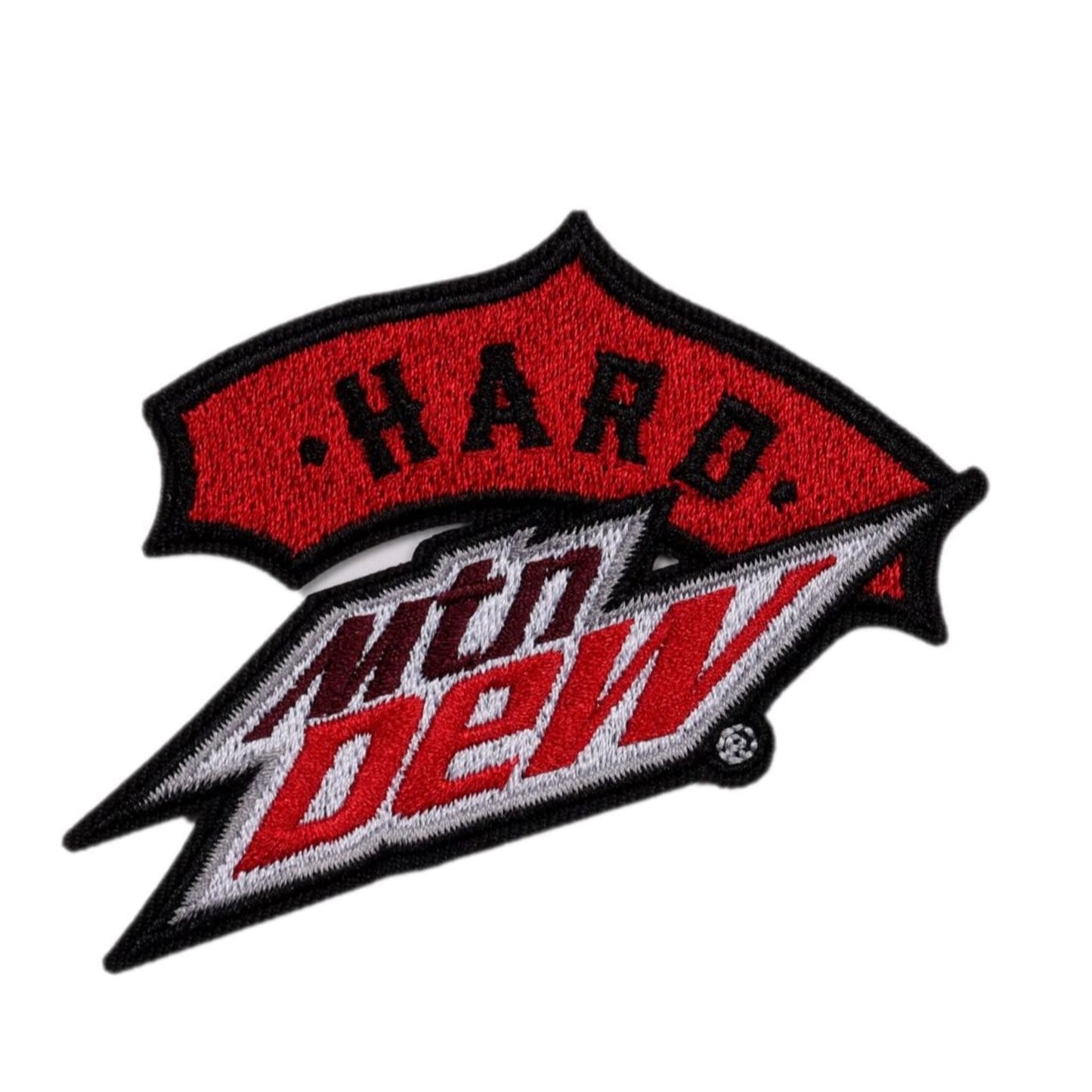 A fabric patch featuring the 'Hard Mtn Dew' logo. The word 'Hard' is in white, block letters on a textured red banner at the top. Below it, the iconic 'Mtn Dew' logo is embroidered in white with red outlines and black accents, designed in a jagged, lightning bolt shape.