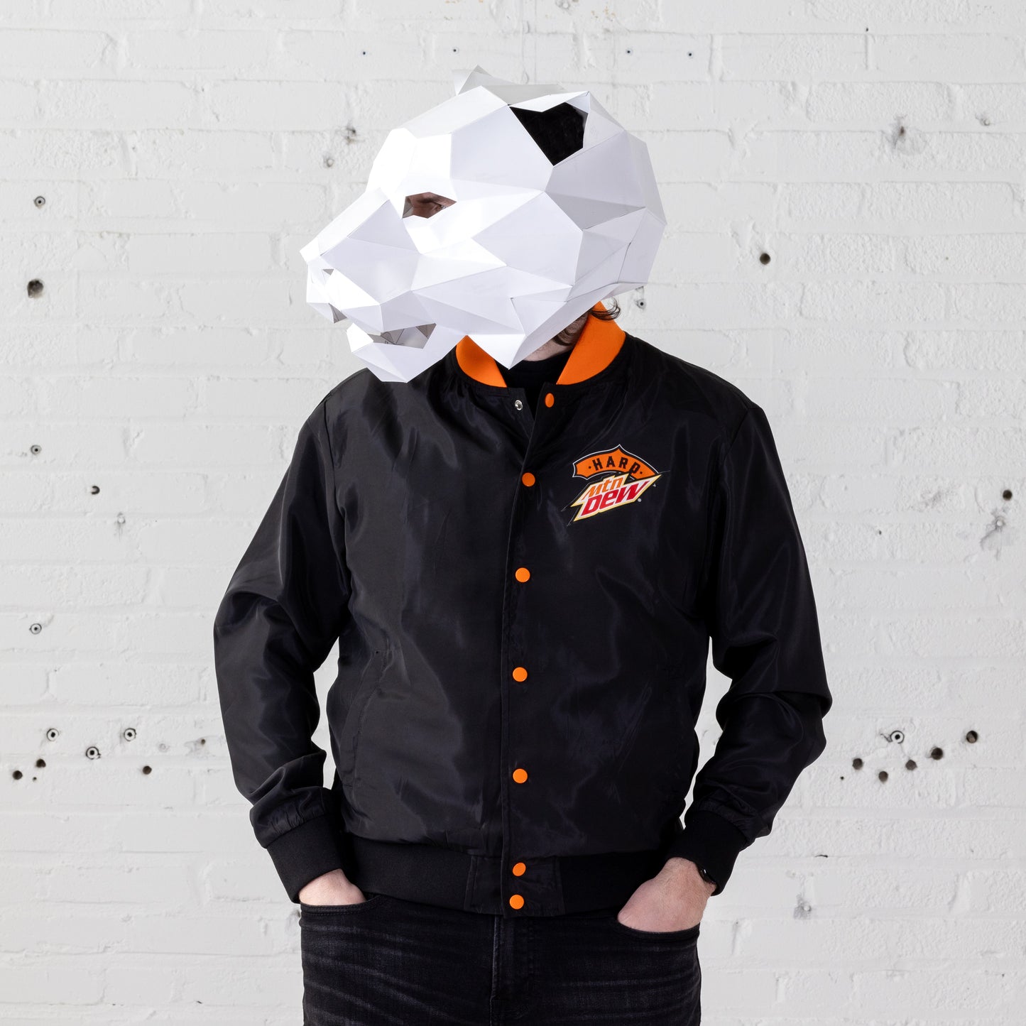 Model wearing a Hard Mountain Dew LiveWire bomber jacket with a white tiger mascot-like mask over their head. The jacket features vibrant colors and a distinctive design.