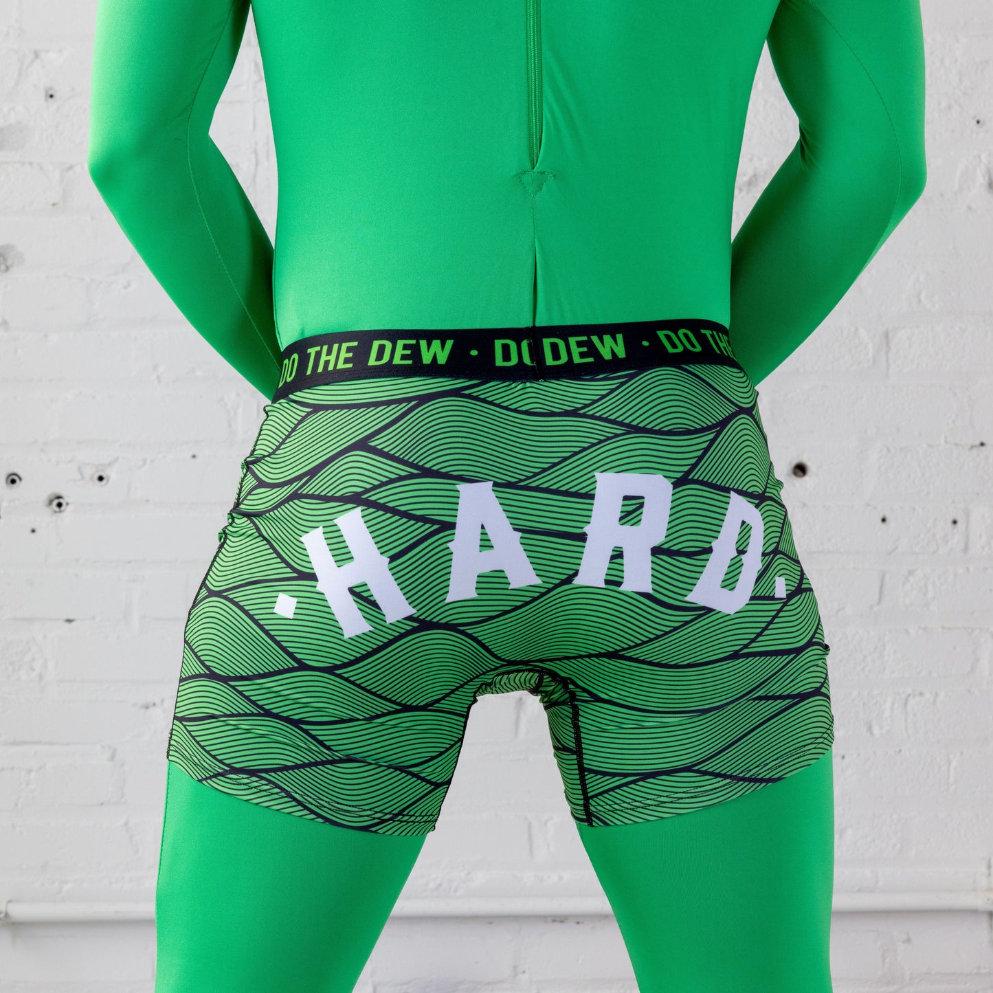 Back view modeled, knit green and black patterned boxer briefs with black waist band. HARD text on rear.
