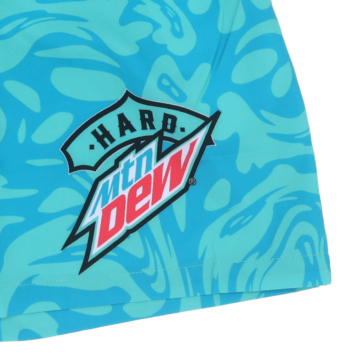 Close-up of the Hard Mountain Dew Baja Blast logo on the front left leg of the swim trunks. The logo is in teal against the water-patterned background.