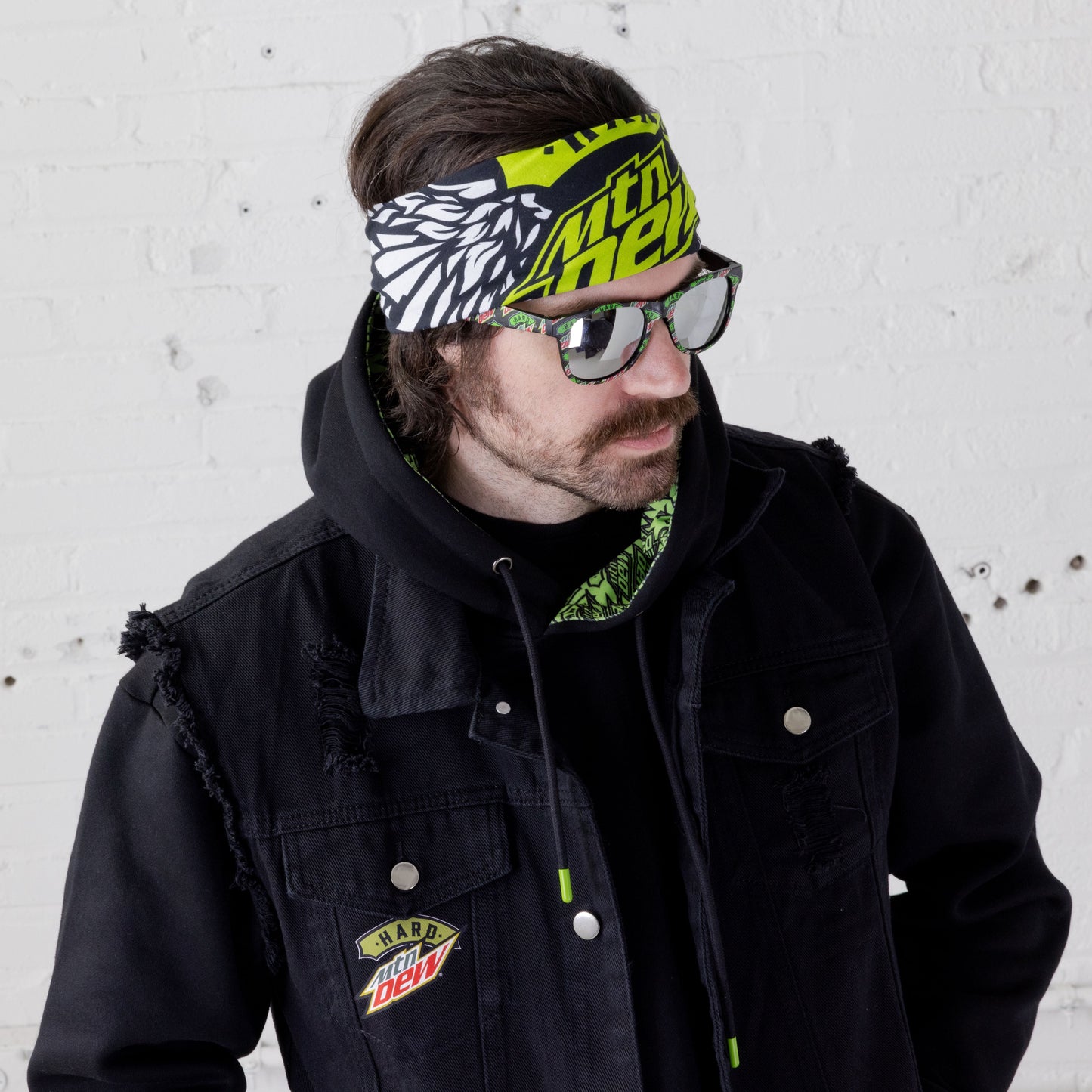 Model wearing a Hard Mountain Dew bandanna in black, white, and neon green. The bandanna features the Hard Mountain Dew logo and an eagle illustration, with the bold colors and graphics clearly visible.