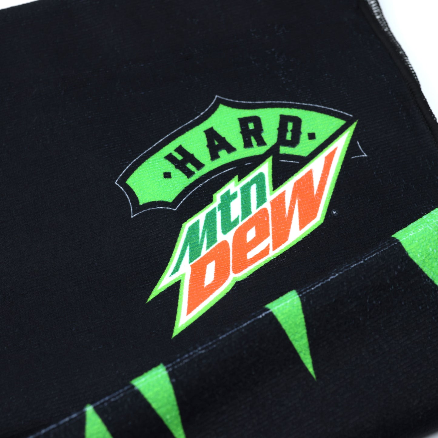 Close-up of the corner of a Hard Mountain Dew towel, highlighting the logo and design details. The corner features bold colors and branding elements.