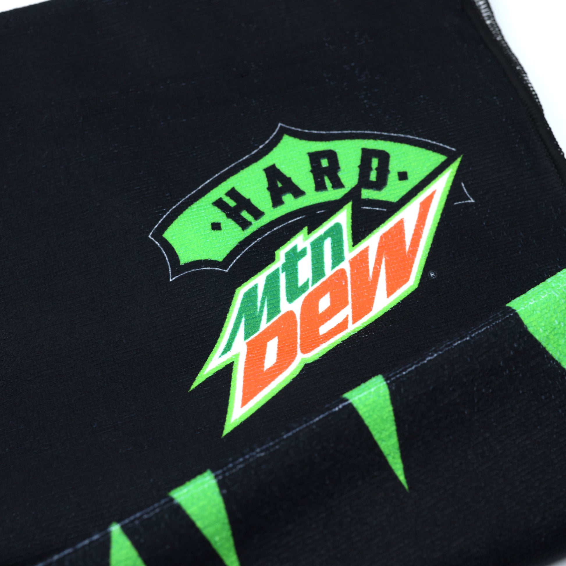 Close-up of the corner of a Hard Mountain Dew towel, highlighting the logo and design details. The corner features bold colors and branding elements.