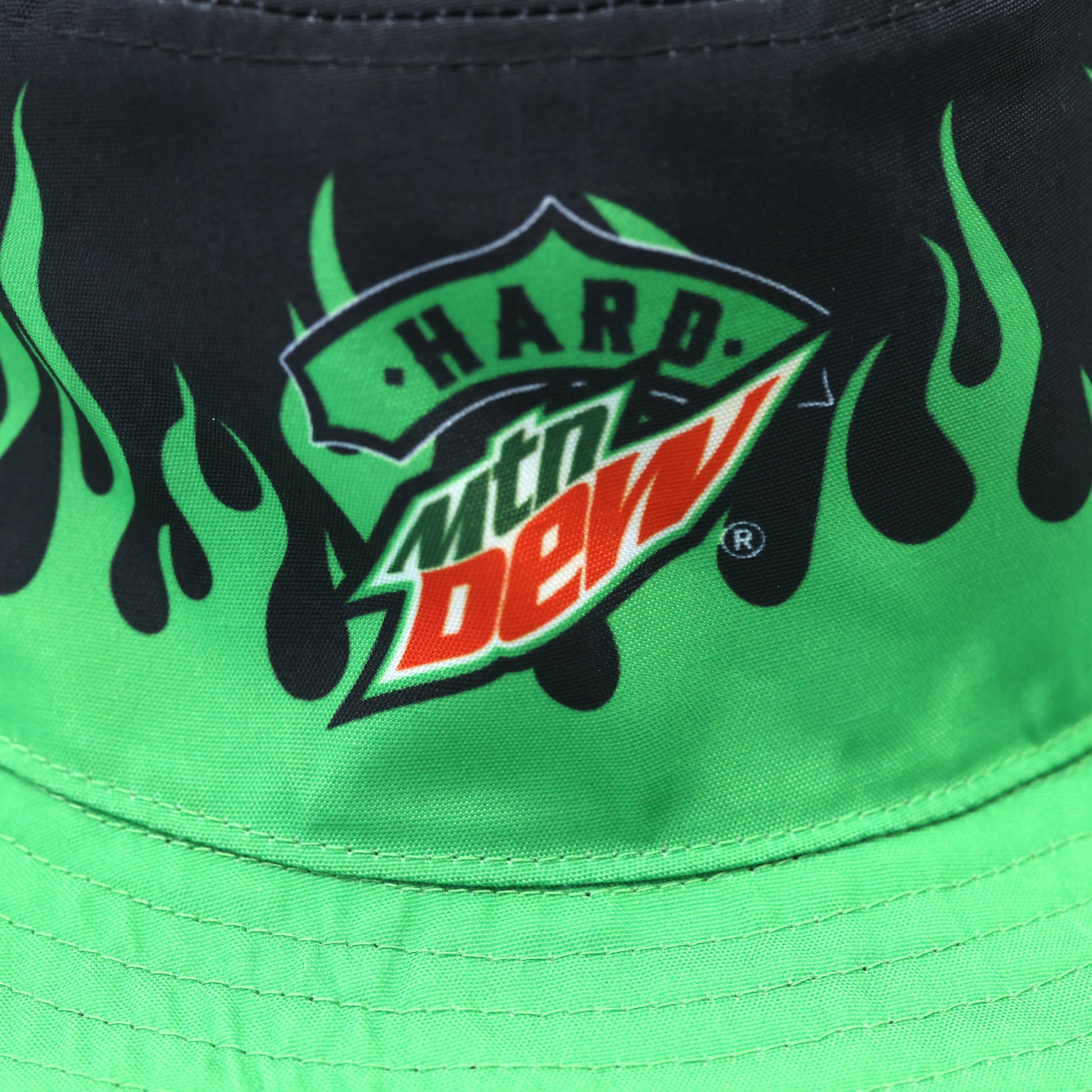 Close-up of the Hard Mountain Dew logo on the side of the bucket hat with green flame patterns. The logo is clearly visible against the flame design.