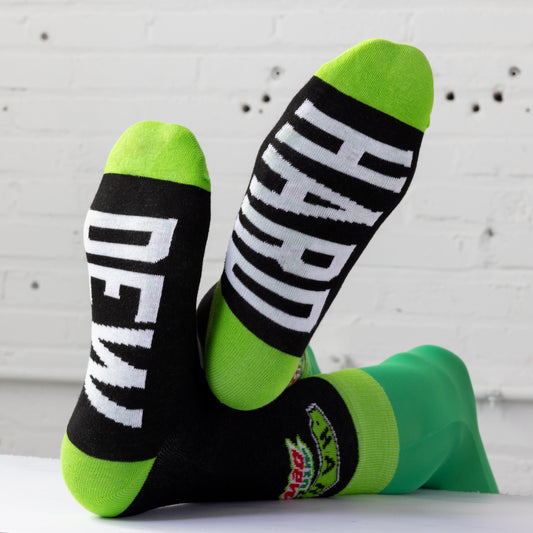 Bottom view of socks worn by a model, showing each foot with a single word. One sock reads 'HARD' and the other reads 'DEW,' with the words prominently displayed.