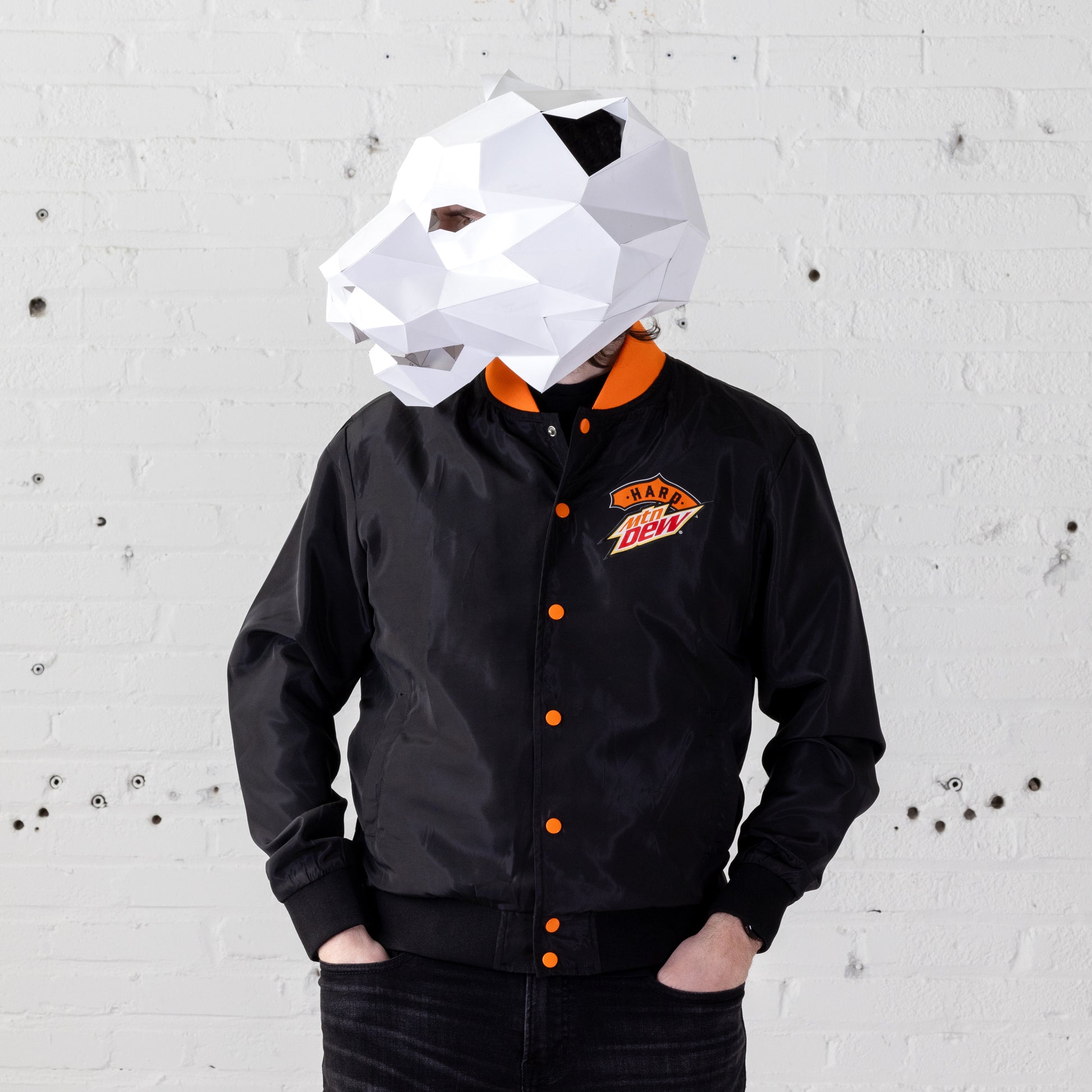 Model wearing a Hard Mountain Dew LiveWire bomber jacket with a white tiger mascot-like mask over their head. The jacket features vibrant colors and a distinctive design.