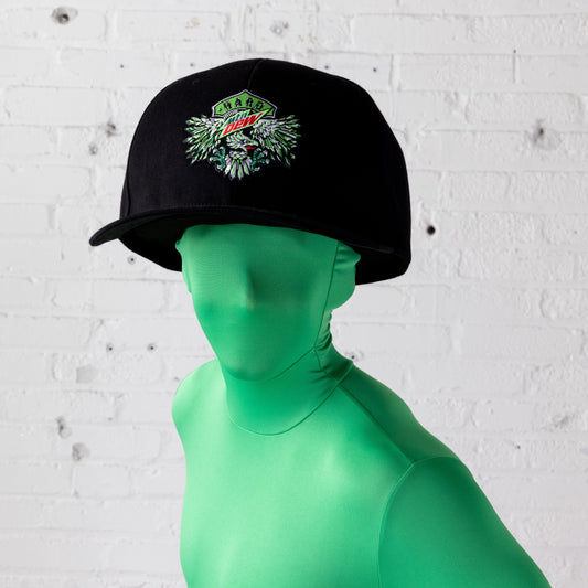 Model wearing a full face-covering bright green skin suit is showcasing the comically oversized black baseball hat. The shot is from the shoulders up, highlighting the hat's large size and its neon green, white, and red eagle and Hard Mountain Dew logo embroidery.
