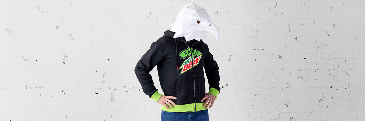 Paper mache eagle mask wearing man wearing a Hard MTN Dew hoodie.